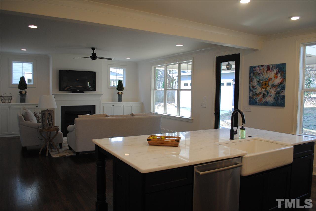 106 Revival Way Raleigh, NC 27608 - Photo 4 of 25 a kitchen with a sink dishwasher a dining table and chairs with wooden floor
