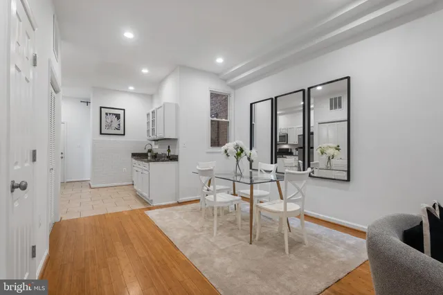 a living room with furniture and a dining table with wooden floor