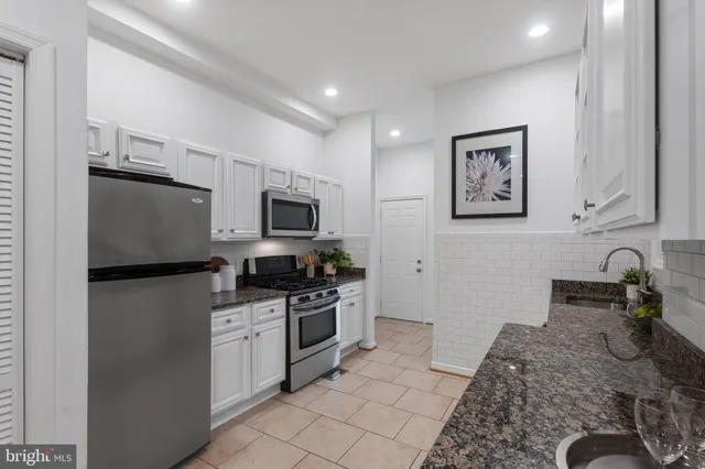 a kitchen with granite countertop white cabinets and stainless steel appliances