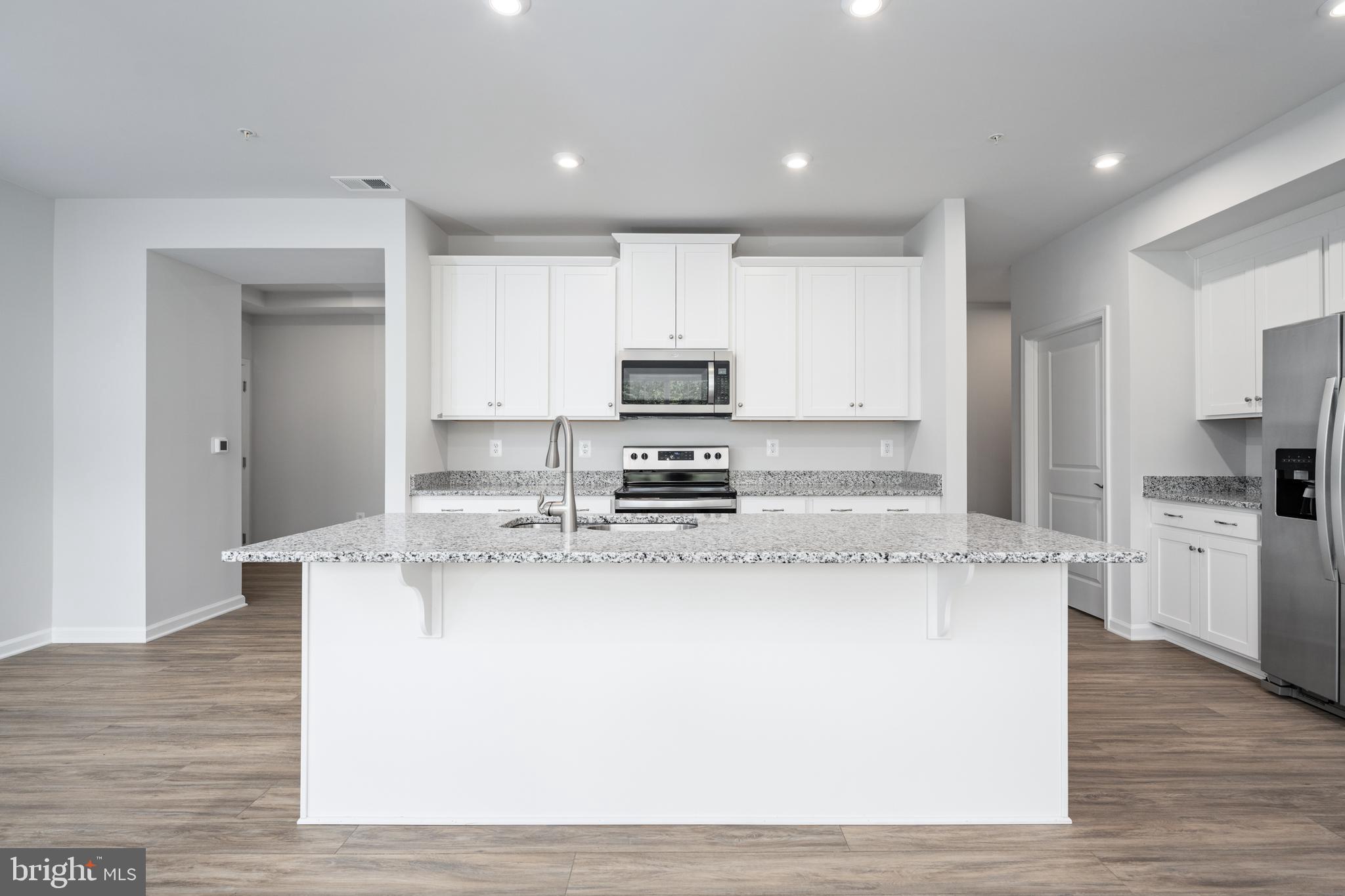 29 Hyssop Way, Unit 103 Stafford, VA 22554 - Photo 13 of 39 a kitchen with kitchen island granite countertop a stove top oven a sink and white cabinets