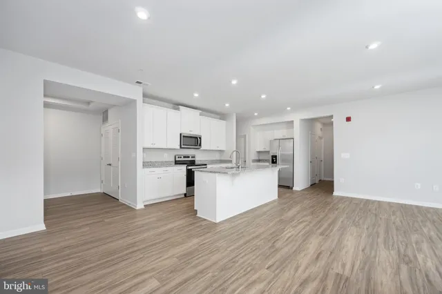 a large kitchen with stainless steel appliances granite countertop a large center island and a wooden floors