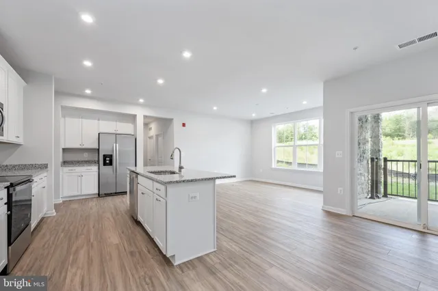 a kitchen with stainless steel appliances granite countertop a stove top oven a sink dishwasher and a microwave oven on the wooden floor