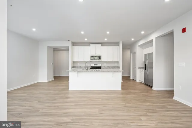 a kitchen with stainless steel appliances granite countertop a sink a stove a microwave and white cabinets