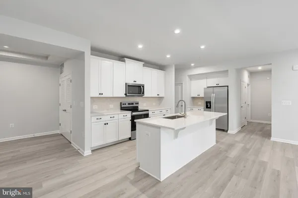 a large kitchen with stainless steel appliances a large counter top a stove and a refrigerator