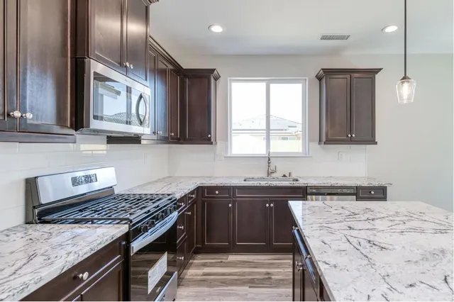 a kitchen with a granite countertop sink window and appliances