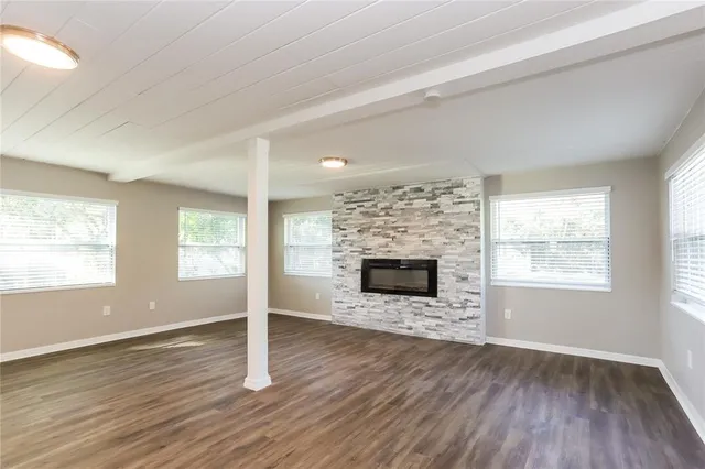 an empty room with wooden floor fireplace and windows