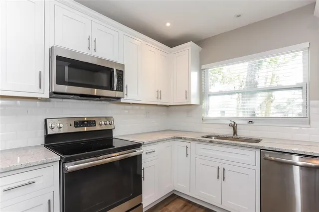 a kitchen with cabinets stainless steel appliances a sink and a window