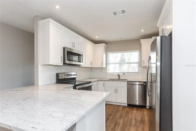 a kitchen with stainless steel appliances granite countertop a sink stove and refrigerator