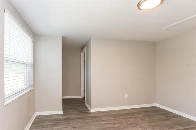 a view of an empty room with wooden floor and a window