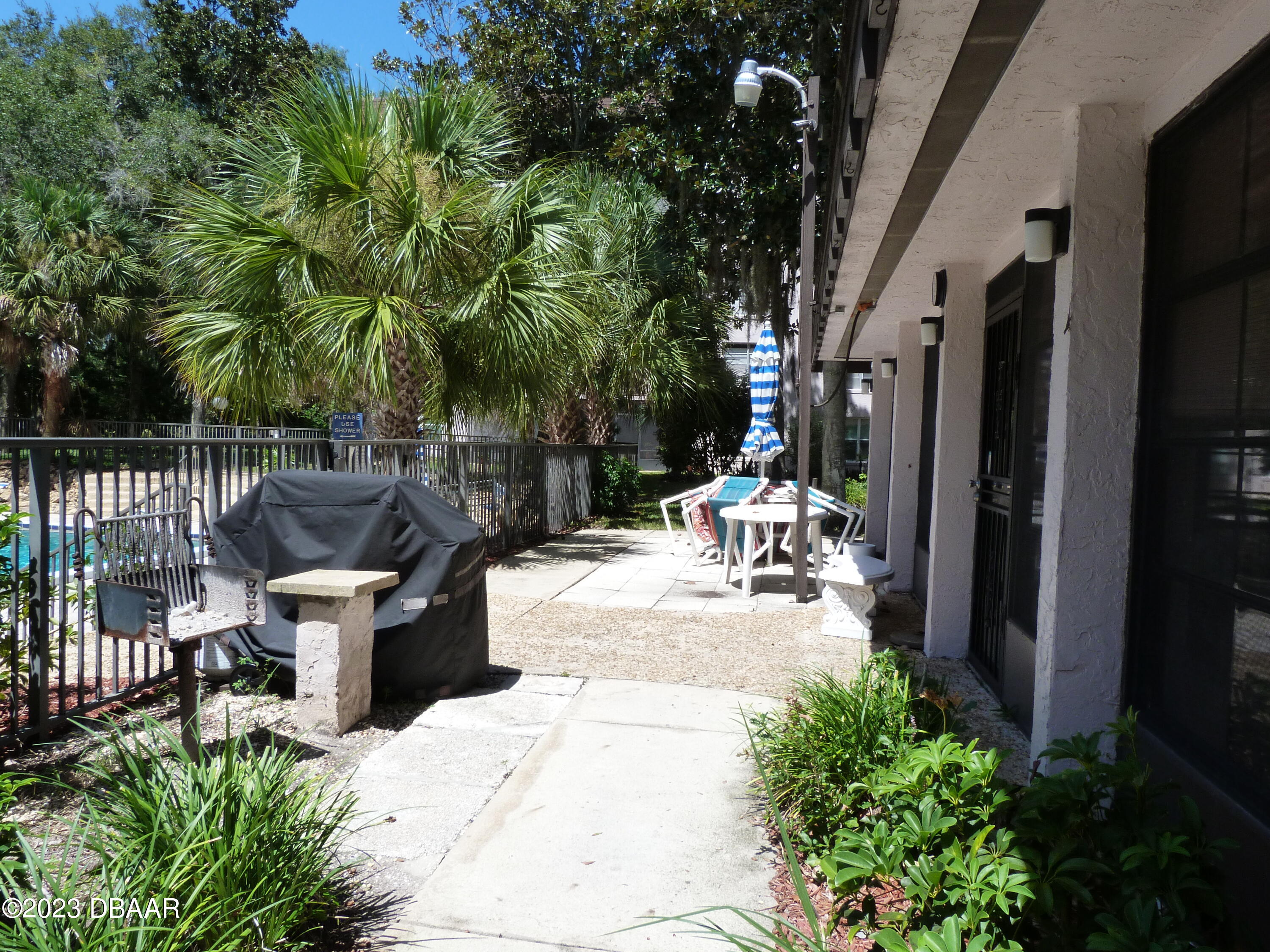 640 North Nova Road, Unit 303 Ormond Beach, FL 32174 - Photo 4 of 31 a view of a patio with table and chairs potted plants and large tree