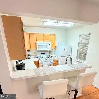 a kitchen with a refrigerator a stove a sink and a dining table with wooden floor