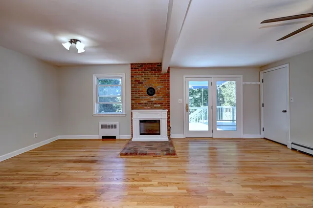 a view of a livingroom with wooden floor a fireplace and windows