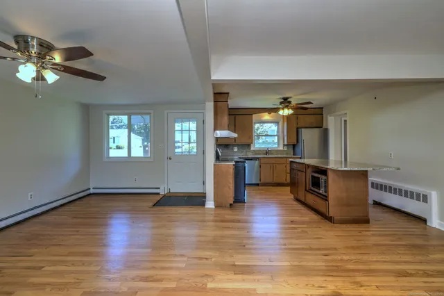 a living room with couches and kitchen view with wooden floor