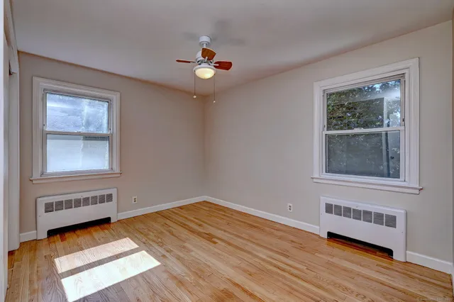 a view of an empty room with wooden floor and a window