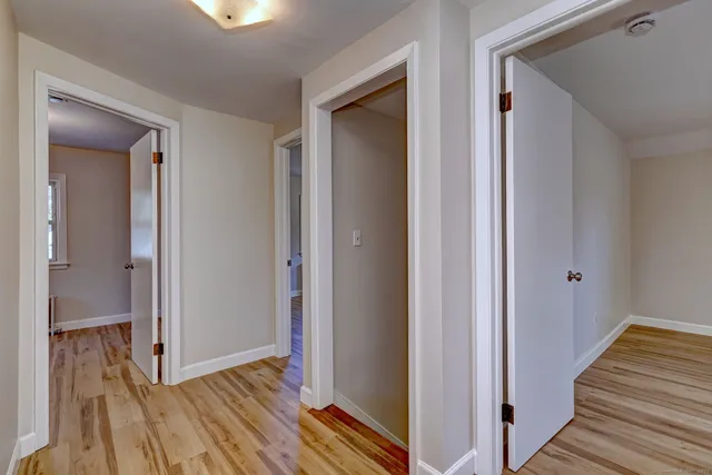 a view of a hallway with wooden floor and closet
