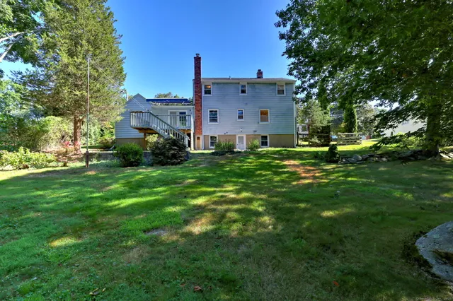 a view of a house with a big yard and large trees
