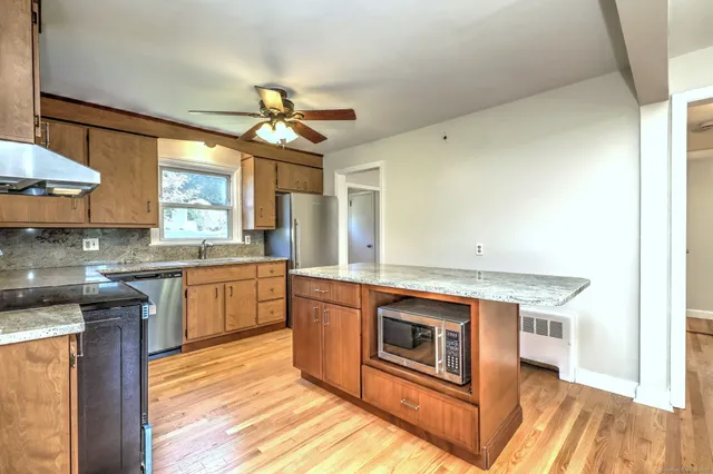 a kitchen with stainless steel appliances granite countertop a stove a sink and a microwave