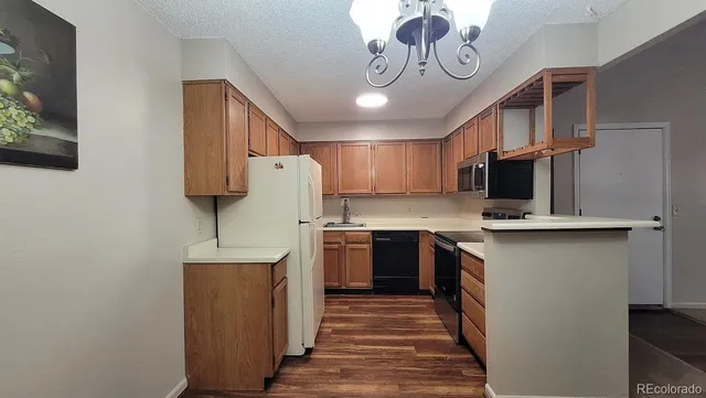 a view of kitchen with stainless steel appliances granite countertop refrigerator stove microwave and cabinets