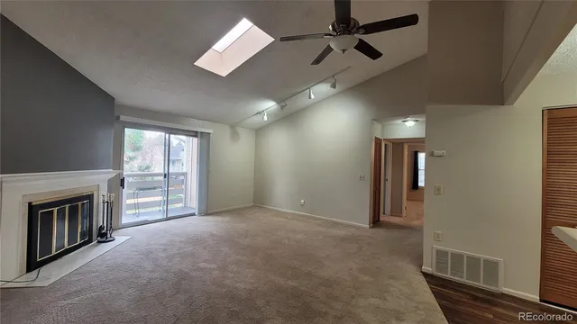 an empty room with windows fireplace and a ceiling fan