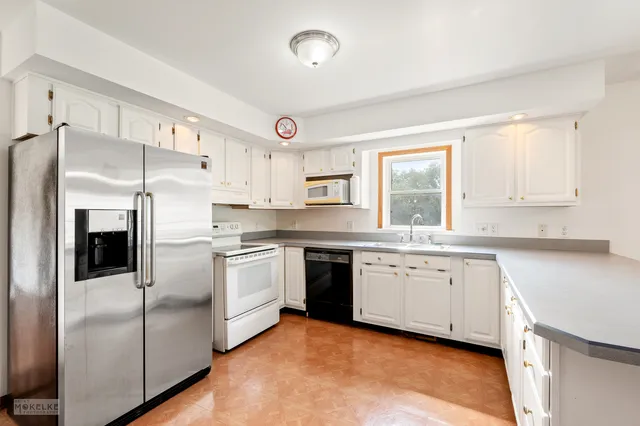 a kitchen with granite countertop a sink stainless steel appliances and window