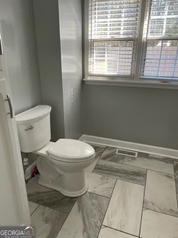 a bathroom with a toilet a sink and a window