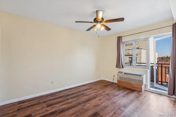 an empty room with wooden floor chandelier fan and windows