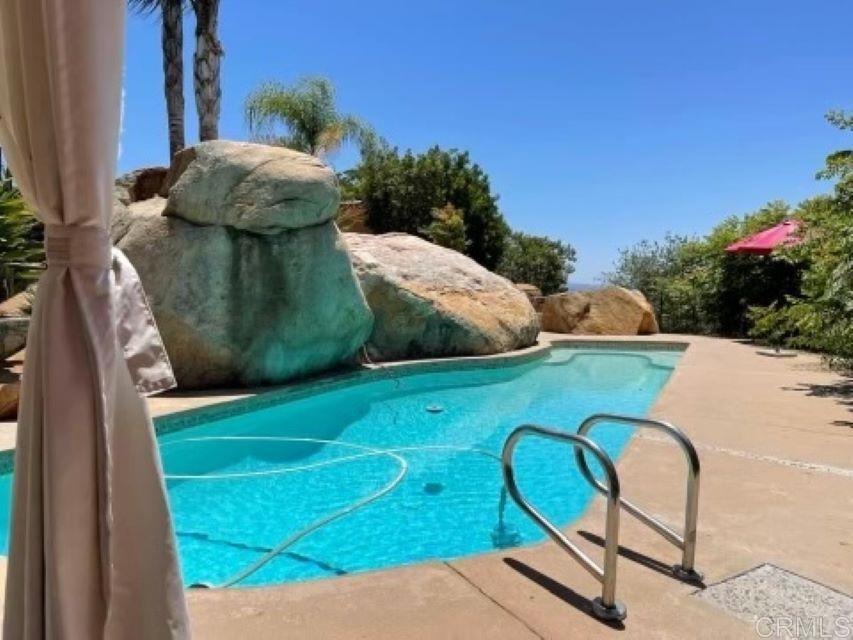 1131 Rainbow Valley Boulevard Fallbrook, CA 92028 - Photo 28 of 73 a view of a swimming pool with a chairs and a table and chairs
