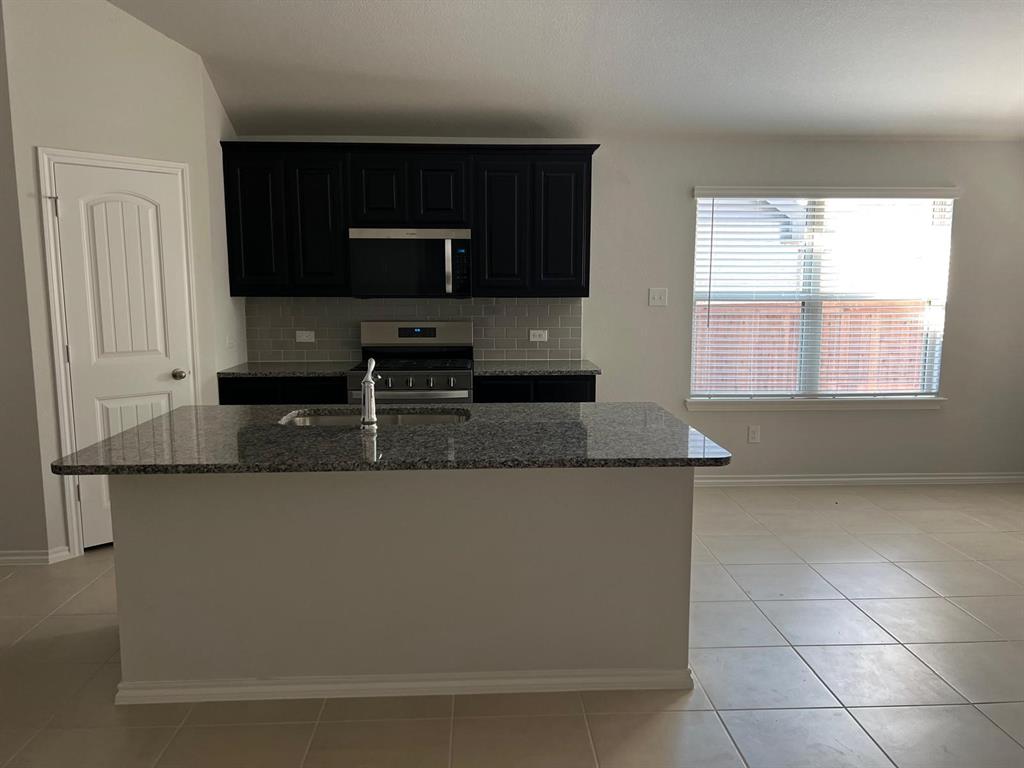 1809 Osage Trail Mesquite, TX 75149 - Photo 3 of 18 a kitchen with stainless steel appliances granite countertop a stove a microwave and a sink