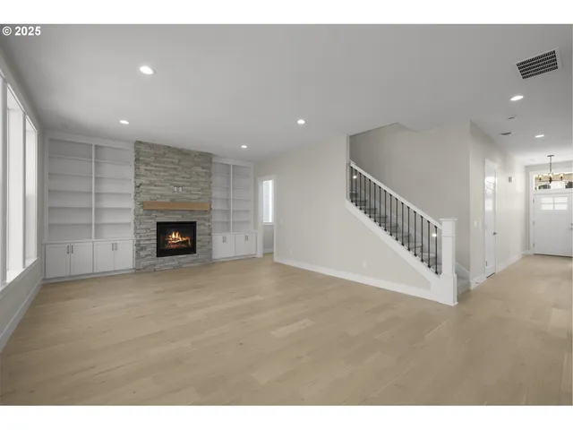 a view of an empty room with wooden floor and a fireplace