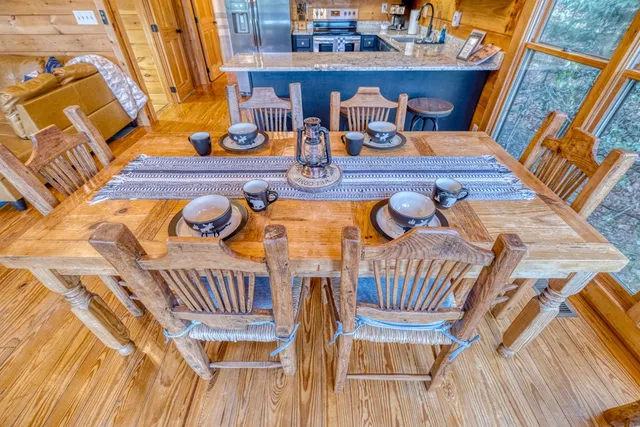 a kitchen with stainless steel appliances granite countertop a stove a refrigerator a sink dishwasher a dining table and chairs with wooden floor