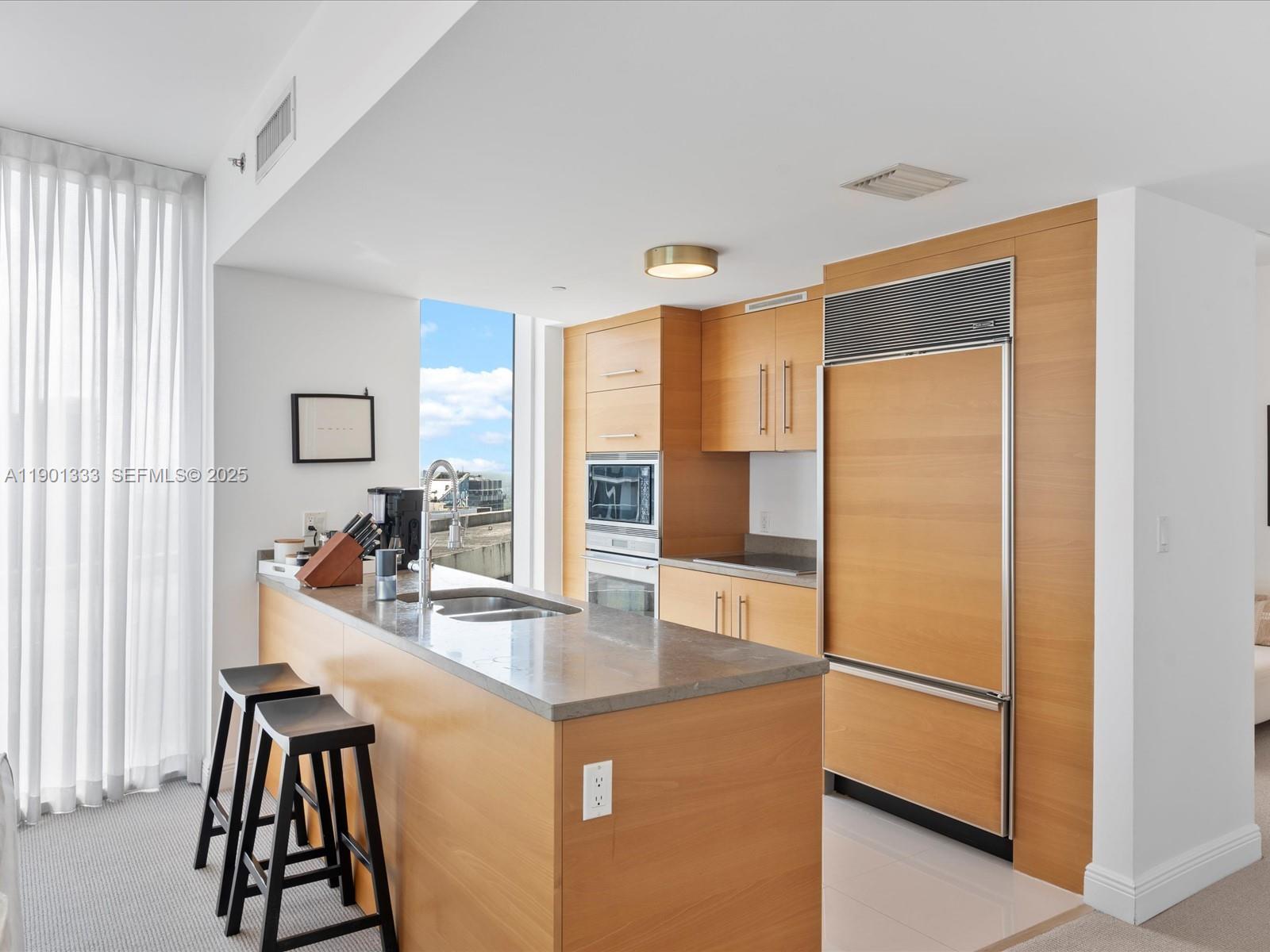 475 Brickell Avenue, Unit 5507 Miami, FL 33131 - Photo 6 of 21 a kitchen with kitchen island a counter top space a sink and a refrigerator