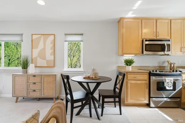 a kitchen with stainless steel appliances kitchen island granite countertop a stove top oven a sink a dining table and chairs