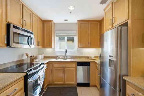 a kitchen with stainless steel appliances granite countertop a stove a sink dishwasher and a refrigerator