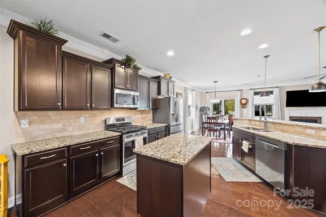 a large kitchen with stainless steel appliances granite countertop a stove refrigerator and cabinets