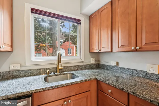 a kitchen with granite countertop a sink a counter space and cabinets