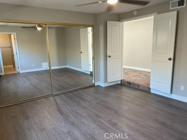 a view of empty room with wooden floor and ceiling fan