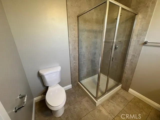 an empty room with wooden floor kitchen view and windows