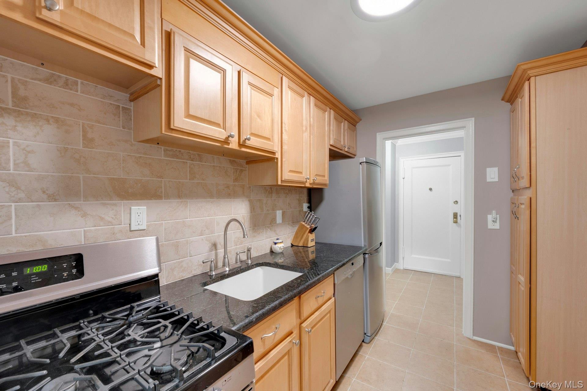 6 Manchester Road, Unit 1 Eastchester, NY 10709 - Photo 15 of 40 Kitchen with appliances with stainless steel finishes, dark stone counters, light tile patterned floors, tasteful backsplash, and light brown cabinetry