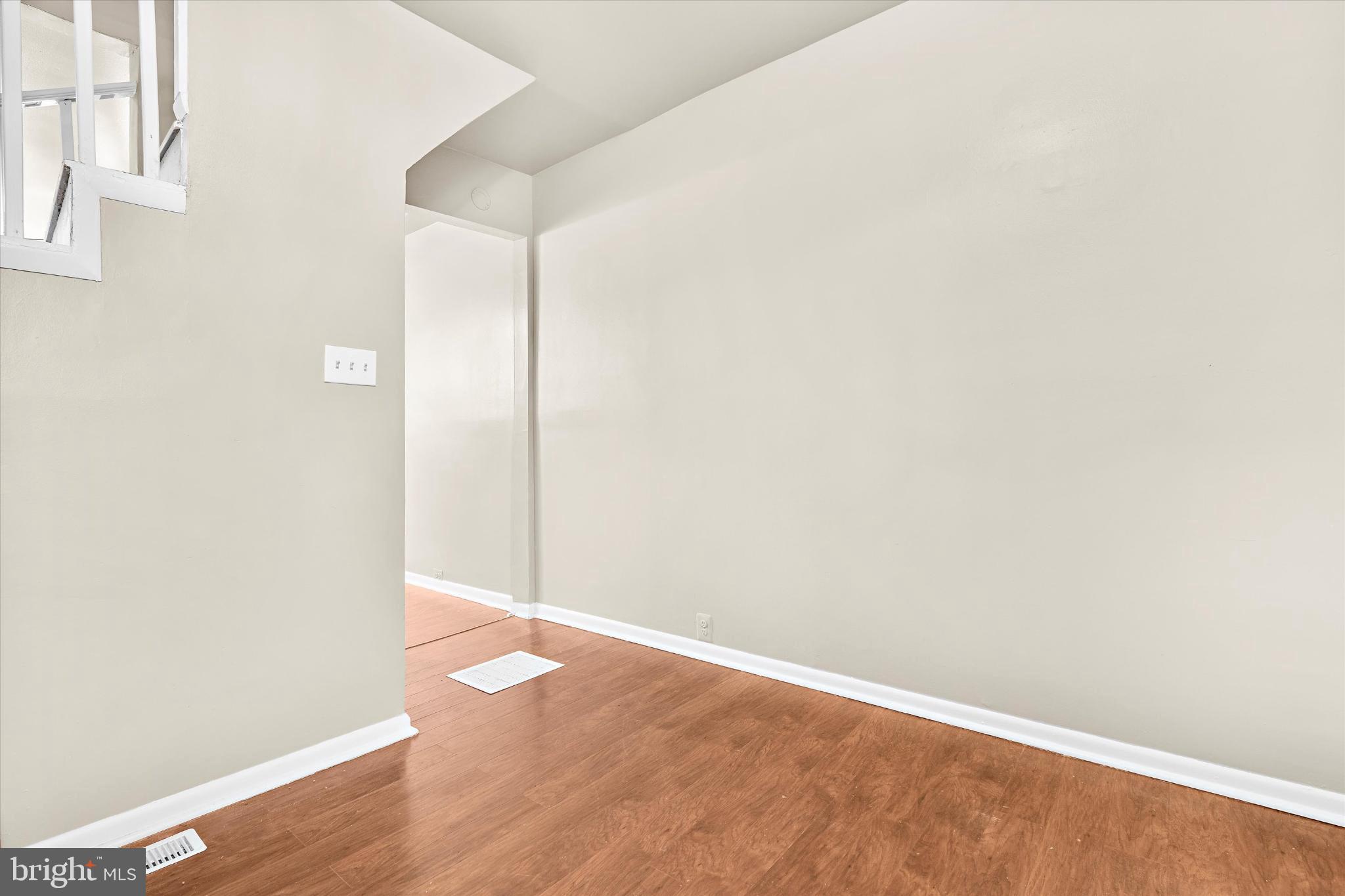 406 Cambria Street Baltimore, MD 21225 - Photo 8 of 26 a view of an empty room with wooden floor and a window