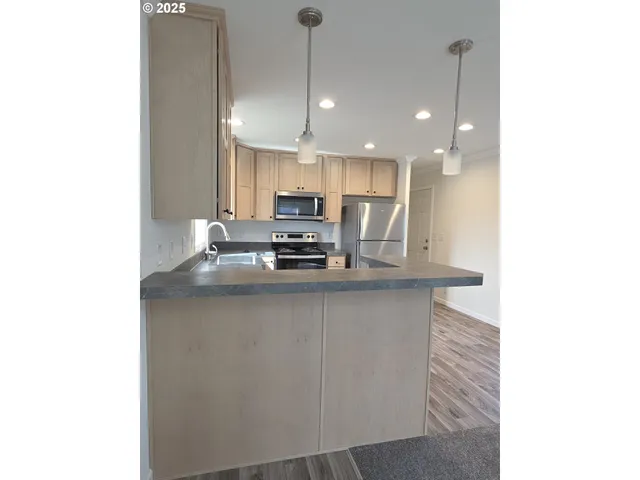 a kitchen with kitchen island stainless steel appliances a sink and cabinets