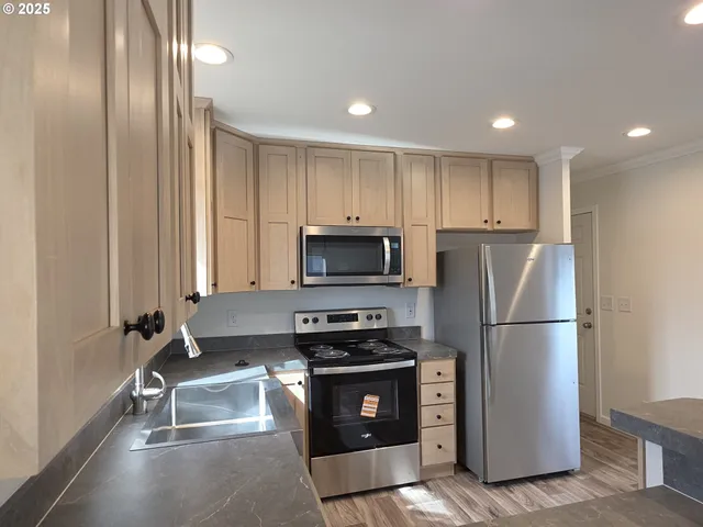 a kitchen with a refrigerator a stove and a sink with wooden floor