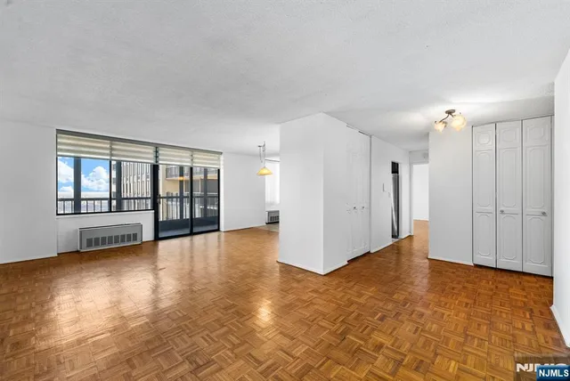a view of an empty room with window and wooden floor