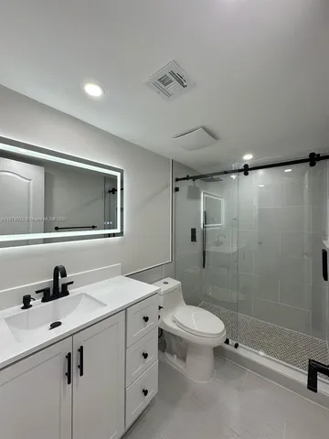 a bathroom with a sink a toilet a mirror and shower