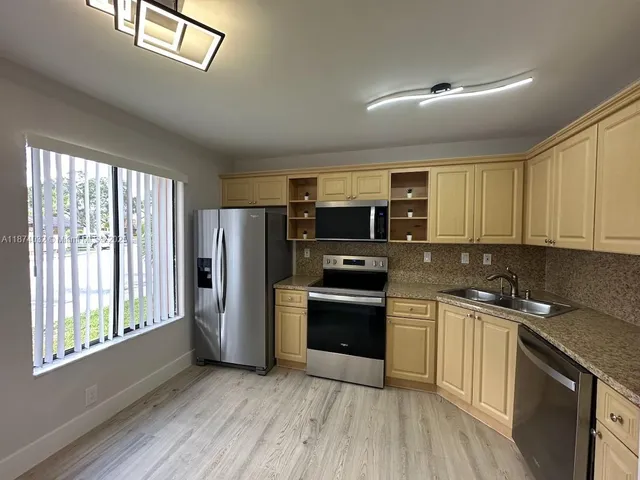 a kitchen with stainless steel appliances granite countertop a stove a sink and a refrigerator