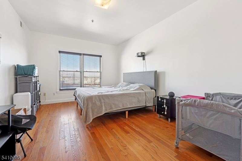 15 Tichenor Street, Unit 407 Newark, NJ 07114 - Photo 21 of 25 a bedroom with a bed and wooden floor
