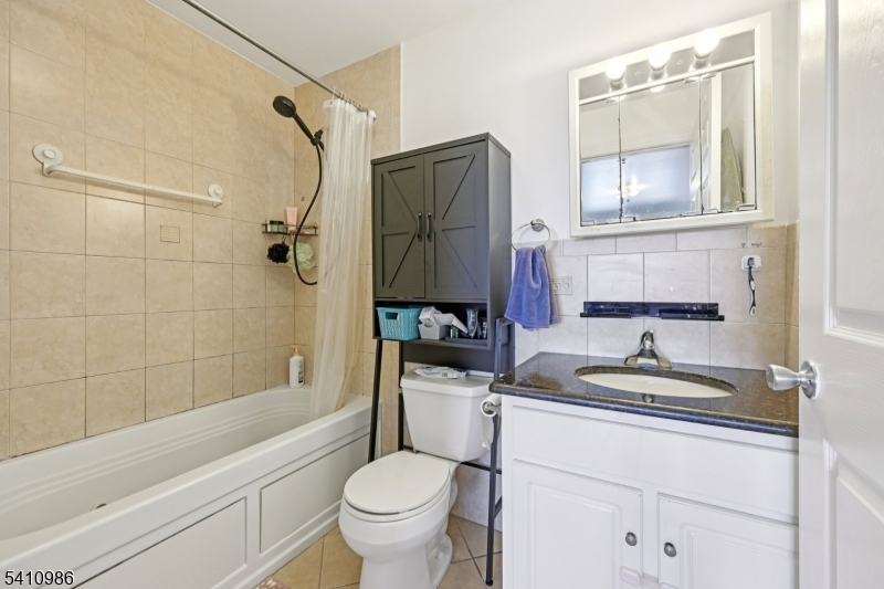 15 Tichenor Street, Unit 407 Newark, NJ 07114 - Photo 23 of 25 a bathroom with a granite countertop sink toilet and shower