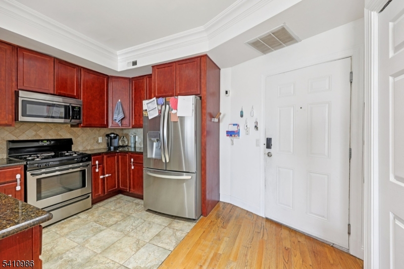 15 Tichenor Street, Unit 407 Newark, NJ 07114 - Photo 10 of 25 a kitchen with granite countertop a refrigerator and a stove top oven