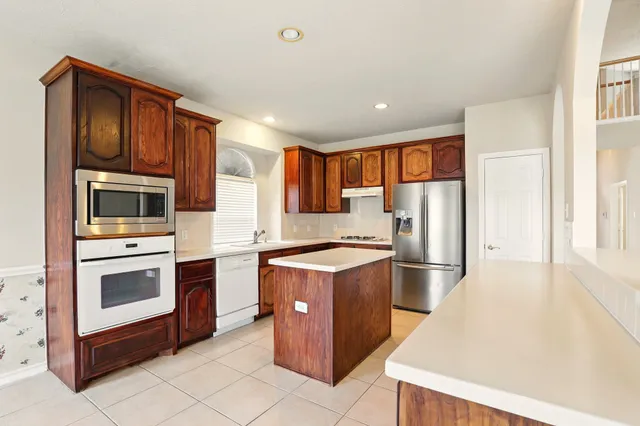a kitchen with stainless steel appliances granite countertop a stove top oven and refrigerator