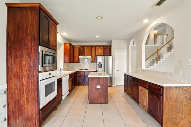 a large kitchen with stainless steel appliances granite countertop a stove a sink dishwasher and a refrigerator