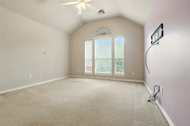 an empty room with windows and chandelier fan